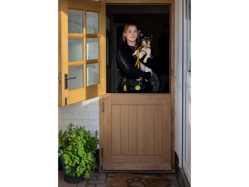 Elizabeth holds a terrier in the doorway of Oakfield Oldies Dogs home